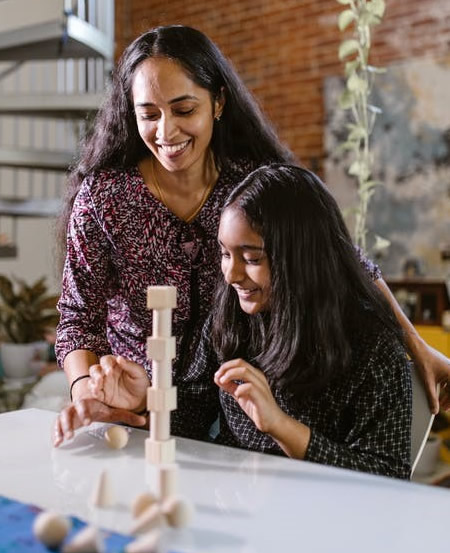 Smiling student stacking blocks with help of an adult.